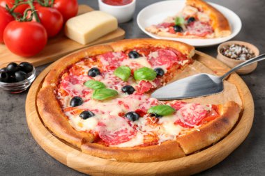 Gri masada lezzetli pizza ve malzemeler, yakın plan.