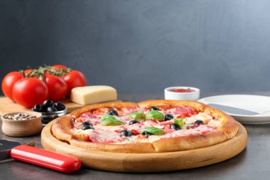 Gri masada lezzetli pizza ve malzemeler, yakın plan.
