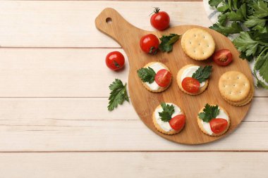 Krem peynirli krakerler, domatesler ve maydanozlu beyaz ahşap masa, düz yatak. Metin için boşluk