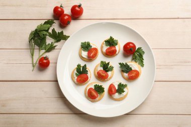 Krem peynirli krakerler, domatesler ve maydanozlar beyaz ahşap masada, düz yatıyordu.