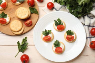 Krem peynirli krakerler, domatesler ve maydanozlar beyaz ahşap masada, düz yatıyordu.