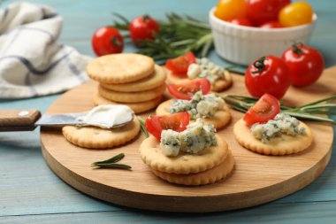 Mavi peynirli krakerler, biberiye ve domatesler ahşap masada, yakın plan.