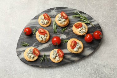 Lezzetli krakerler mavi peynirli, biberiye ve domatesler gri desenli masa, üst manzara