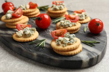 Lezzetli krakerler mavi peynirli, biberiyeli ve domatesli gri desenli masa, yakın plan.