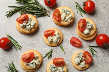 Lezzetli krakerler mavi peynirli, biberiyeli ve domatesli gri desenli masa, düz.