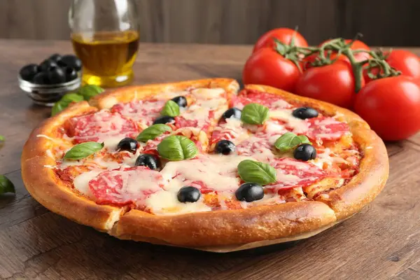 Lezzetli pizza ve malzemeler ahşap masada, yakın plan.