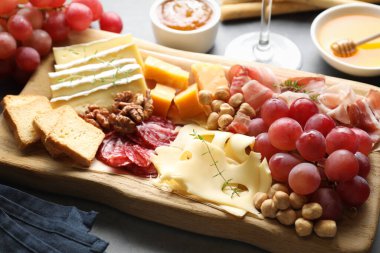 Gri masada değişik kesim peynir ve diğer atıştırmalıklar, yakın plan.