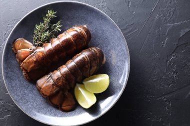 Çiğ ıstakoz kuyruğu, kireç ve kekik siyah masada, üst manzara. Metin için boşluk