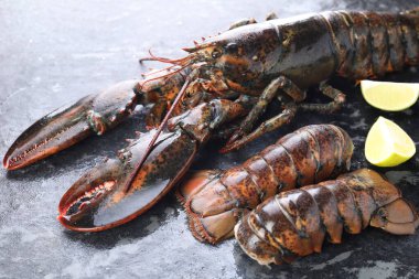 Çiğ ıstakoz, kuyruk ve kireç karanlık masada, yakın plan.