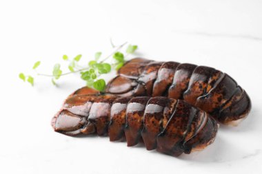 Beyaz mermer masada çiğ ıstakoz kuyruğu ve mikro yeşiller, yakın plan.