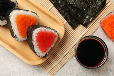 Lezzetli tobiko onigiri (Japon pirinç topları) açık gri masada servis edilir.