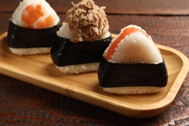 Lezzetli onigiri (Japon pirinç topları) ahşap masada servis edilir, yakın plan.
