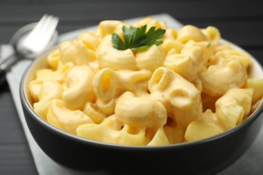 Siyah ahşap masada servis edilen maydanozlu lezzetli makarna ve peynir.