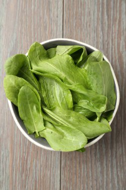 Taze yeşil kuş yaprakları kasede, ahşap masada, üst tarafta.