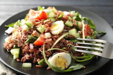 Siyah ahşap masada kahverengi pirinçli leziz salata, yakın plan.