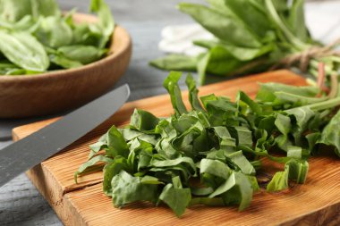 Gri ahşap masada taze kuş yaprakları ve bıçak kes, yakın plan.