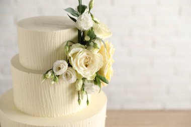 Bulanık arka planda çiçeklerle süslenmiş lezzetli düğün pastası, yakın plan. Metin için boşluk