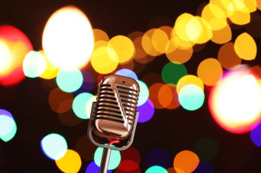 Karanlık arka planda bulanık ışıkları olan klasik mikrofon, mesaj için yer. Müzik ekipmanları