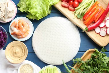 Pirinç kağıt çarşaflar ve mavi ahşap masa üzerindeki farklı malzemeler.