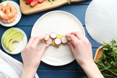 Mavi ahşap masada nefis börek yapan bir kadın.