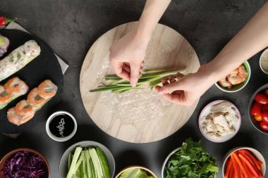 Koyu gri masada nefis börek yapan bir kadın.