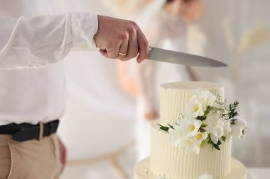 Evli çift içeride bıçakla lezzetli bir düğün pastası kesiyor.