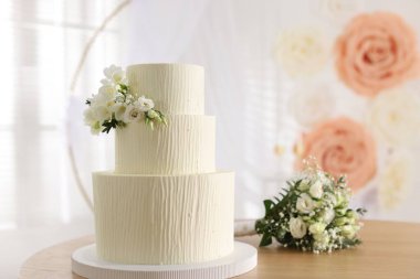 Çiçek desenli nefis düğün pastası ve ahşap masa üzerinde buket.