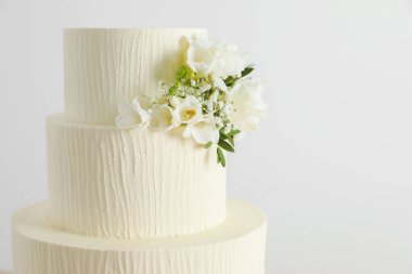 Beyaz arka planda çiçeklerle süslenmiş nefis düğün pastası, yakın plan. Metin için boşluk