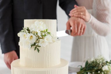 Yeni evliler içeride düğün pastasını kesiyorlar. Seçici bir odak noktası.