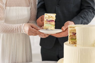 Damat, düğün pastasının bir parçasını tabağa koyuyor. Gelini içeride tutuyor, yakın plan.