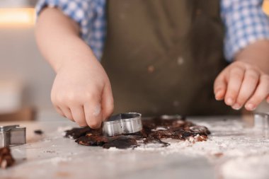 Yemek tarifi. Kurabiye hamurunu masanda kesen küçük çocuk, yakın plan.