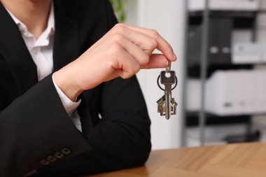 Ev anahtarı olan bir emlakçı, kapalı bir masada, yakın plan. Metin için boşluk