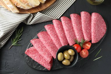 Siyah masada servis edilen zeytinli ve domatesli leziz sosis dilimleri.