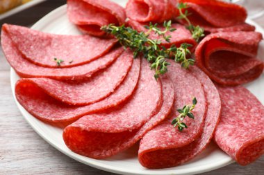 Hafif ahşap masada servis edilen kekik dilimli lezzetli sosisler.