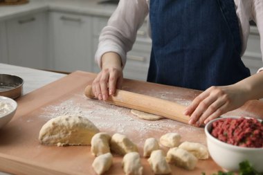 Khinkali yapıyorum. Mutfaktaki masada merdane şekilli hamuru olan kadın, yakın plan.