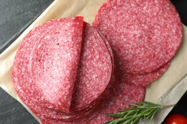 Lezzetli tütsülenmiş sosis ve biberiye dilimleri siyah masada, üst tarafta.