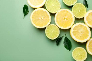 Soluk yeşil arka planda limon ve limon dilimleri, düz. Metin için boşluk