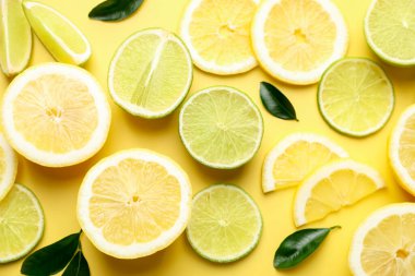 Sarı arka planda limon ve limon dilimleri, düz uzanmış.