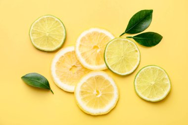Sarı arka planda limon ve limon dilimleri, düz uzanmış.