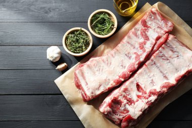 Çiğ domuz pirzolası, deniz tuzu, yağ, sarımsak ve otlar siyah ahşap masa üzerinde, düz yatıyordu.