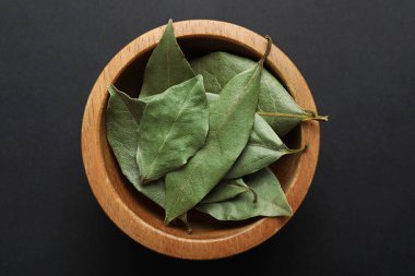 Aromatik körfez yaprakları kasede koyu masada, üst tarafta.