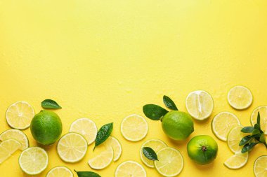 Taze limon ve yeşil yapraklar sarı arka planda, düz yerde. Metin için boşluk