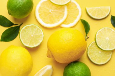 Taze limon, limon ve yeşil yapraklar sarı arka planda, düz yerde