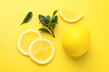 Taze limon ve yeşil yapraklar sarı arka planda, düz yatıyordu.