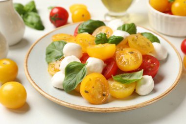 Taze salata, sarı domates, fesleğen ve mozzarella peyniri beyaz masada, yakın plan.