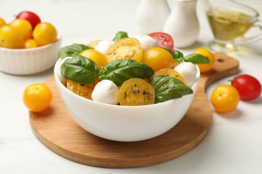 Taze salata, sarı domates, fesleğen ve mozzarella peyniri beyaz masada, yakın plan.