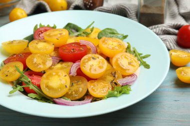 Açık mavi ahşap masada sarı domatesli taze salata, yakın plan.