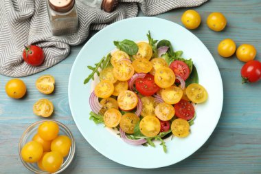 Açık mavi ahşap masada servis edilen yeşil domatesli taze salata.