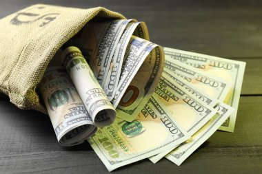 Üzerinde dolar banknotları olan para çantası. Gri ahşap masa, yakın plan.