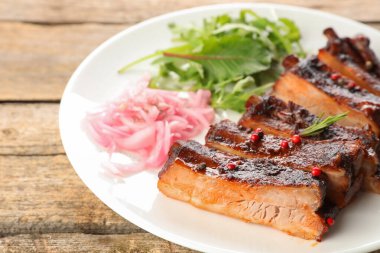 Lezzetli domuz pirzolası, roka ve soğan ahşap masada, yakın plan.